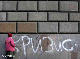 Чаша терпения белорусов далеко не полна, говорят эксперты Женщина стоит перед стеной, на которой написано Кризис